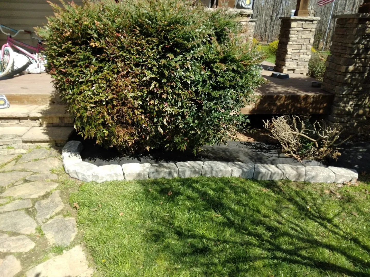 Rounded shrub and curved stone border during a landscape bed installation.