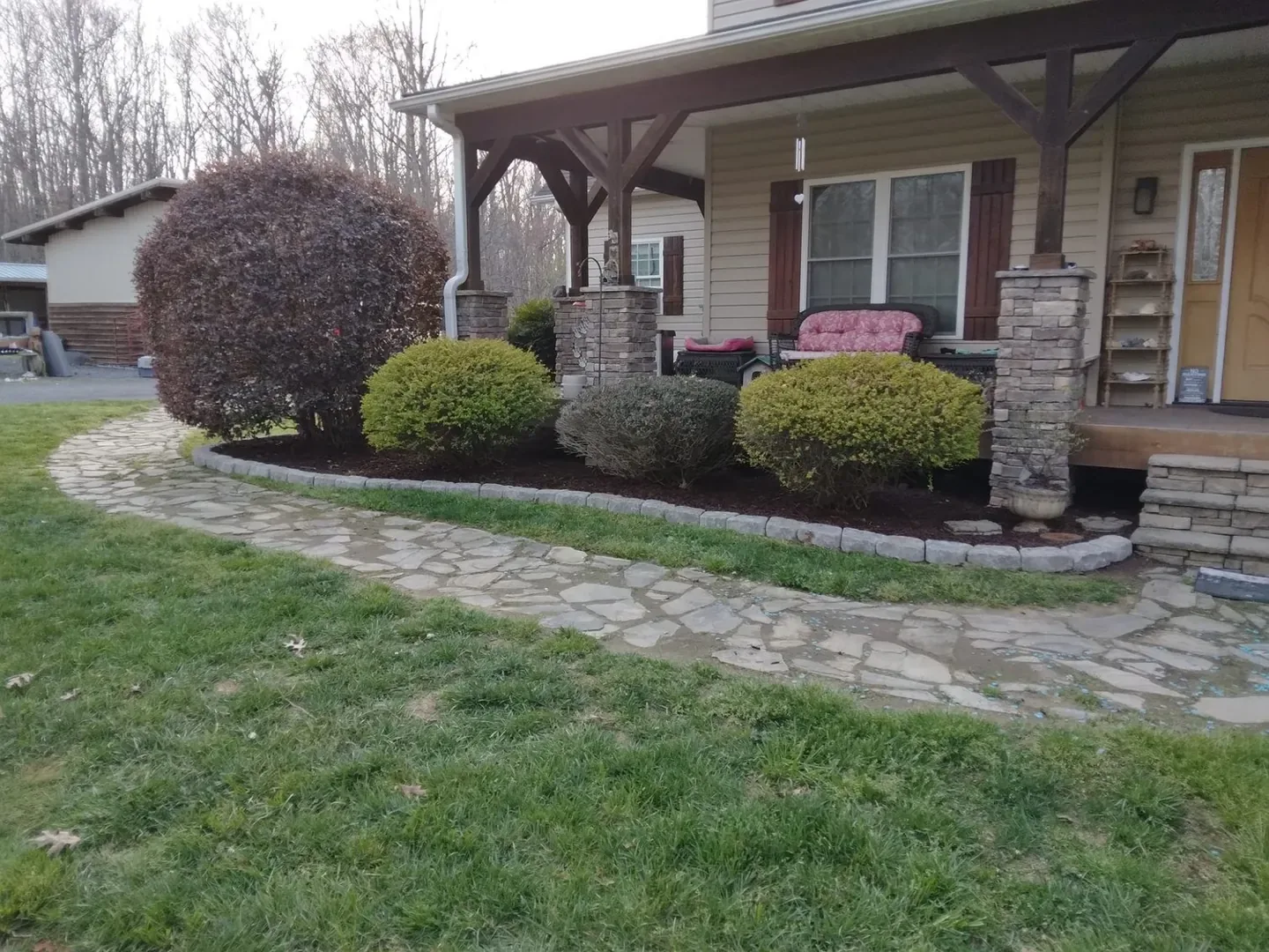 Completed stone edging and fresh mulch around shaped shrubs.