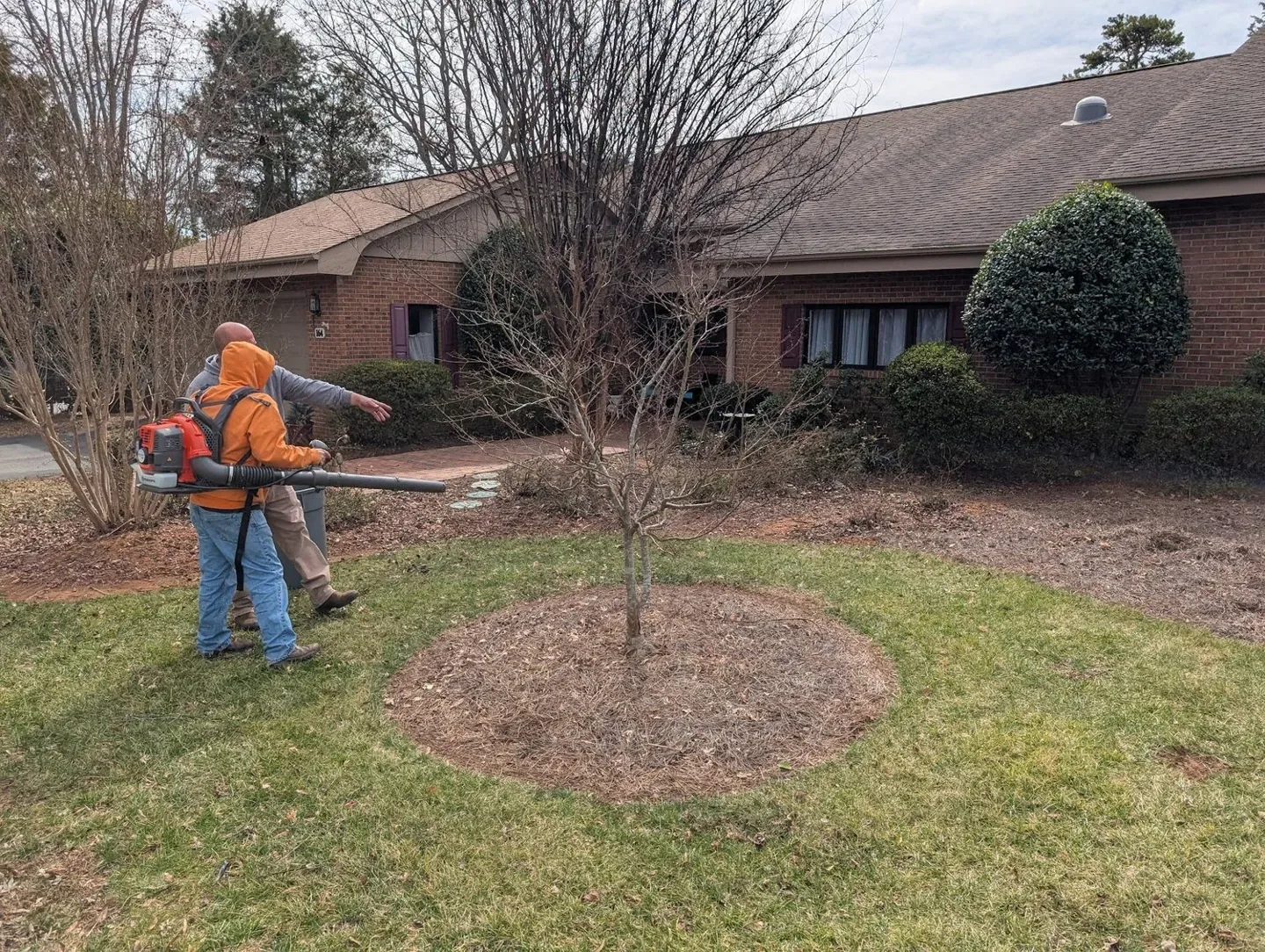 Crew working on a landscape bed beside a brick building.