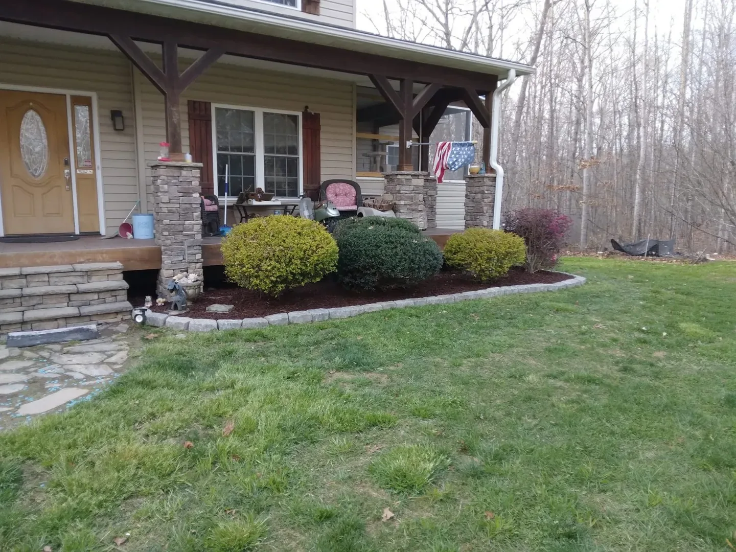New stone edging around shrubs beside a front porch.
