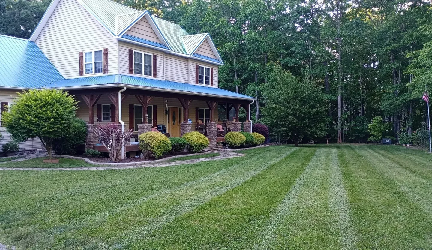 Striped front lawn and trimmed landscape beds around a two-story home.