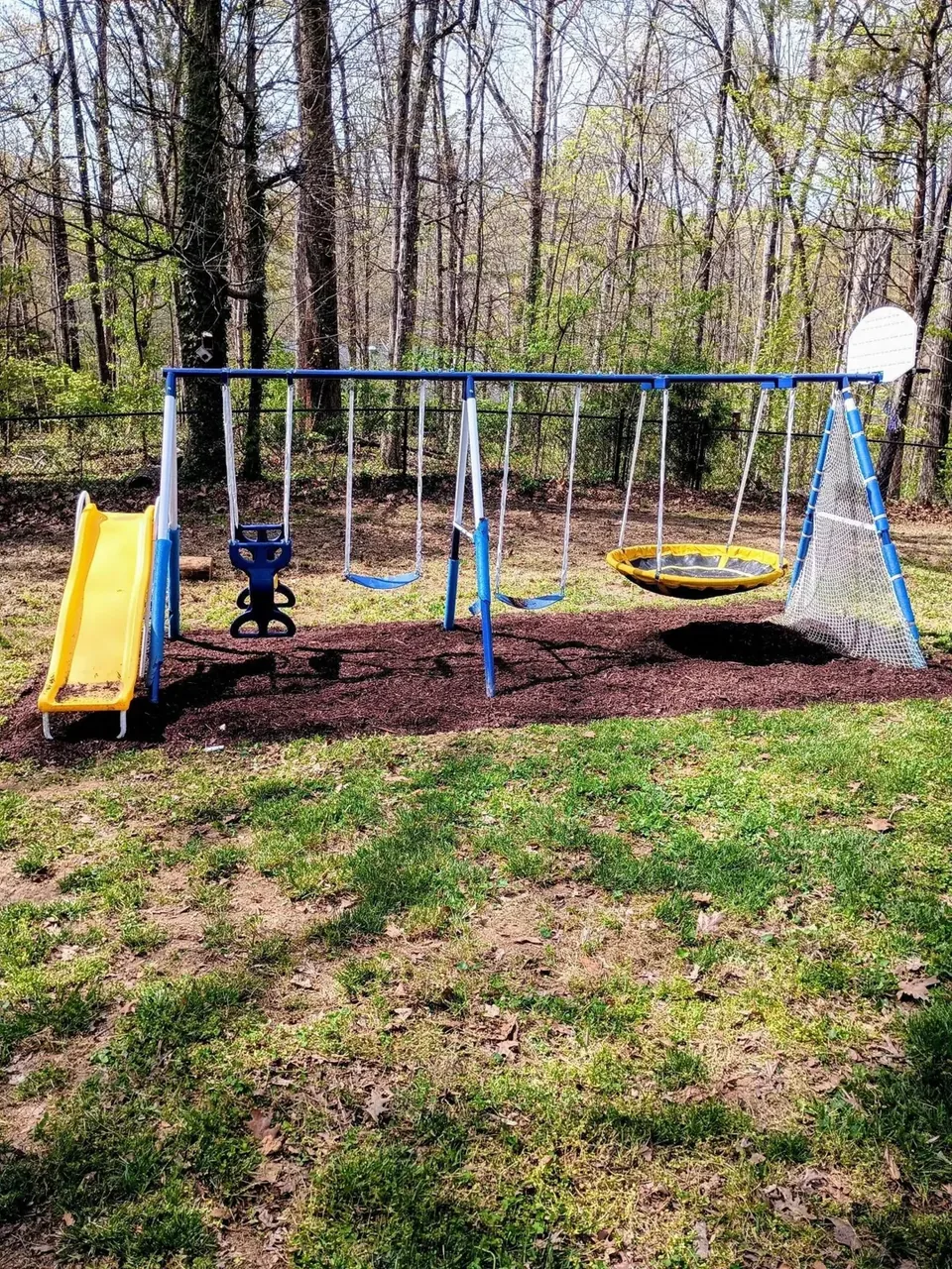 Edged bed and weed barrier around a backyard playset before mulching.