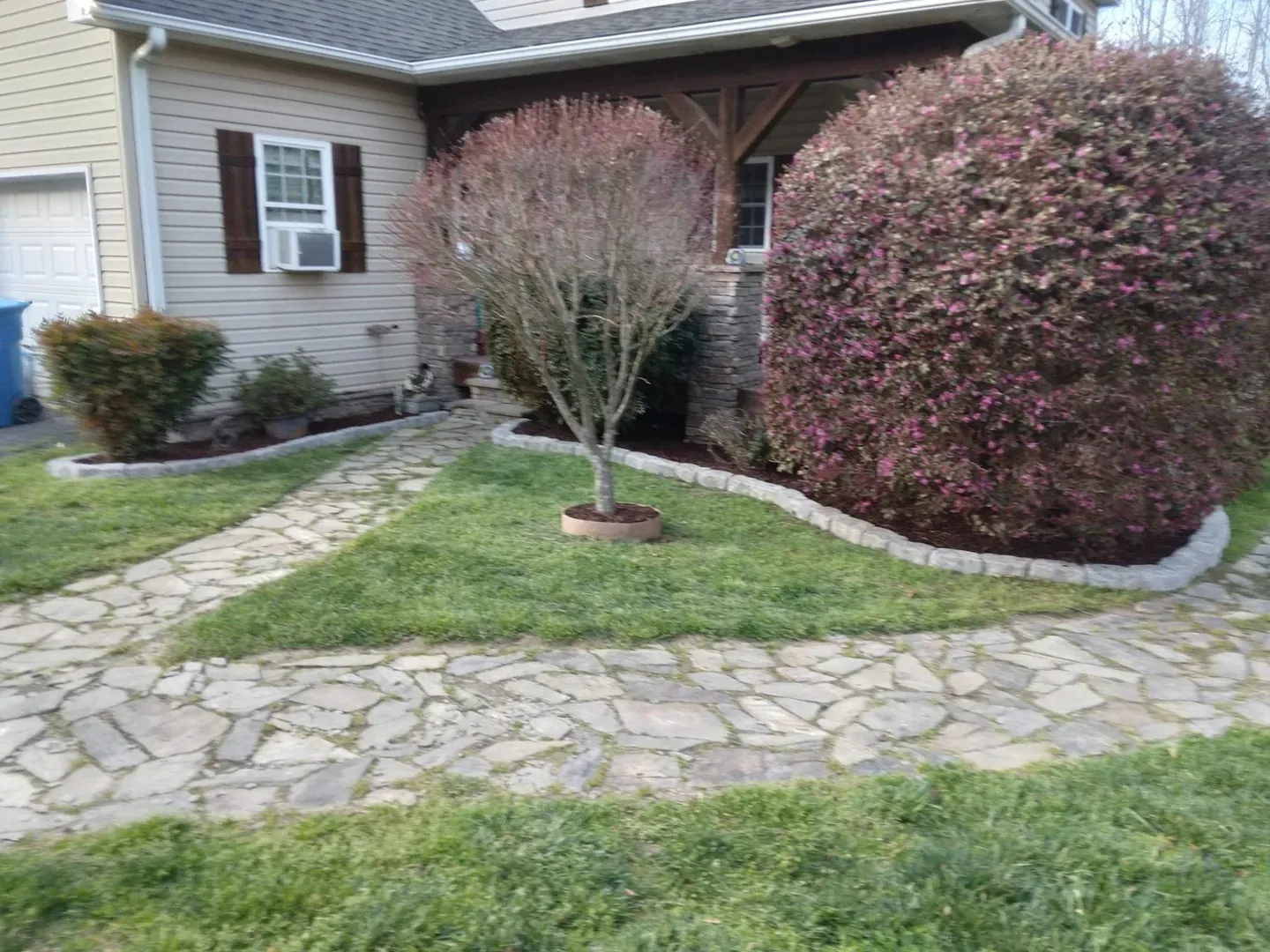 New stone edging around a planting bed with trimmed shrubs.