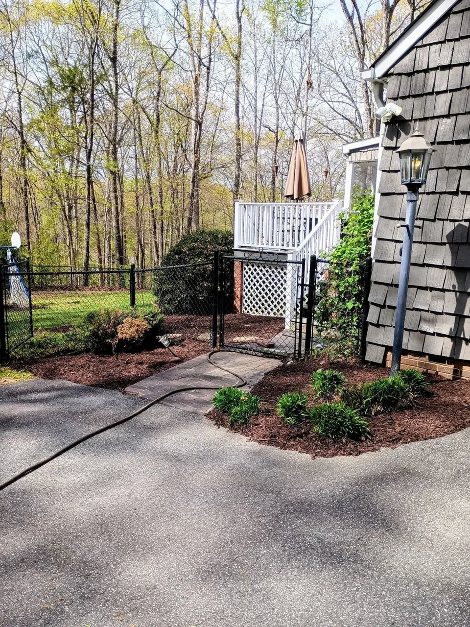 After cleanup: fresh mulch and a tidy planting bed beside the backyard patio.